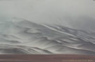 An image of slopes covered by snow which dissolve in the white, foggy sky.